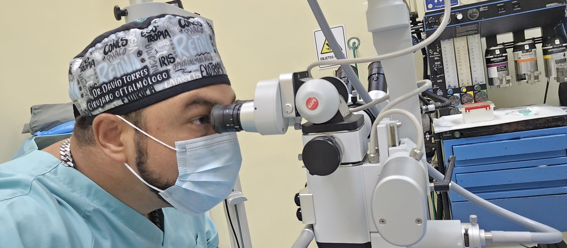 El Dr. Torres en el quirófano, mirando por el microscopio durante una cirugía ocular